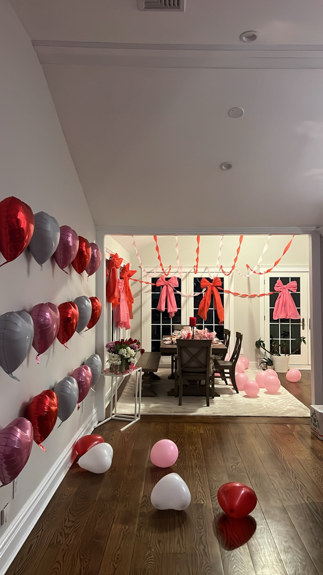 Valentine's room with red, pink and silver heart balloon wall and oversized bows on the windows