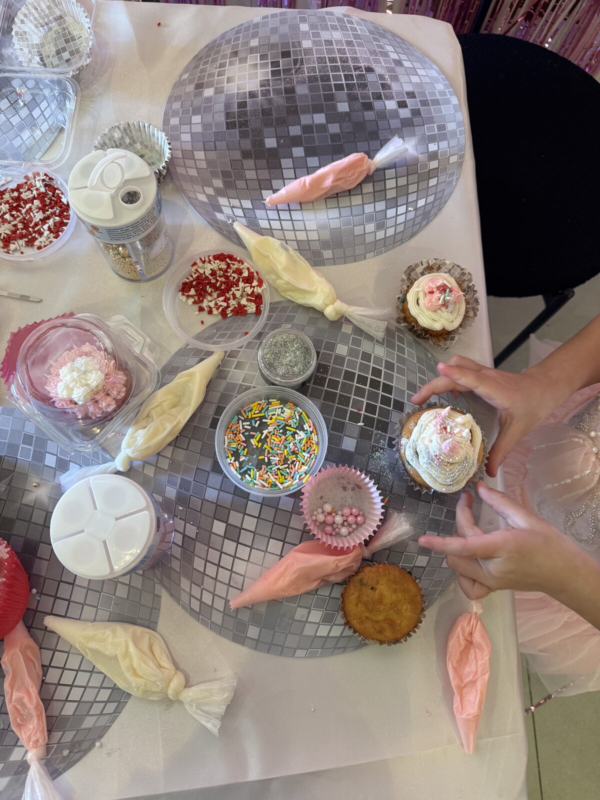 Top-down view of disco-ball platters with cupcakes, sprinkles, glitter and piping bags